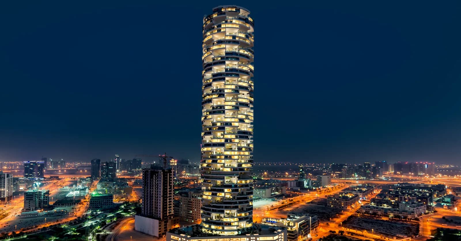 FIVE Jumeirah Village tower lit at night above the Jumeirah Village Circle skyline