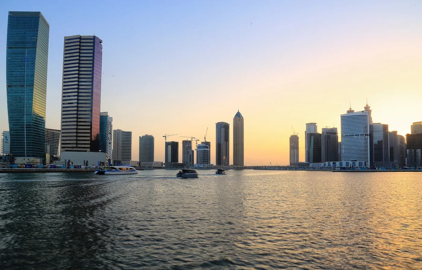 Dubai Water Canal in Business Bay at golden hour with boats and towers