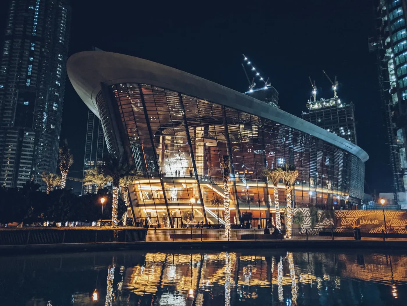 Dubai Opera facade glowing at night with Downtown towers behind