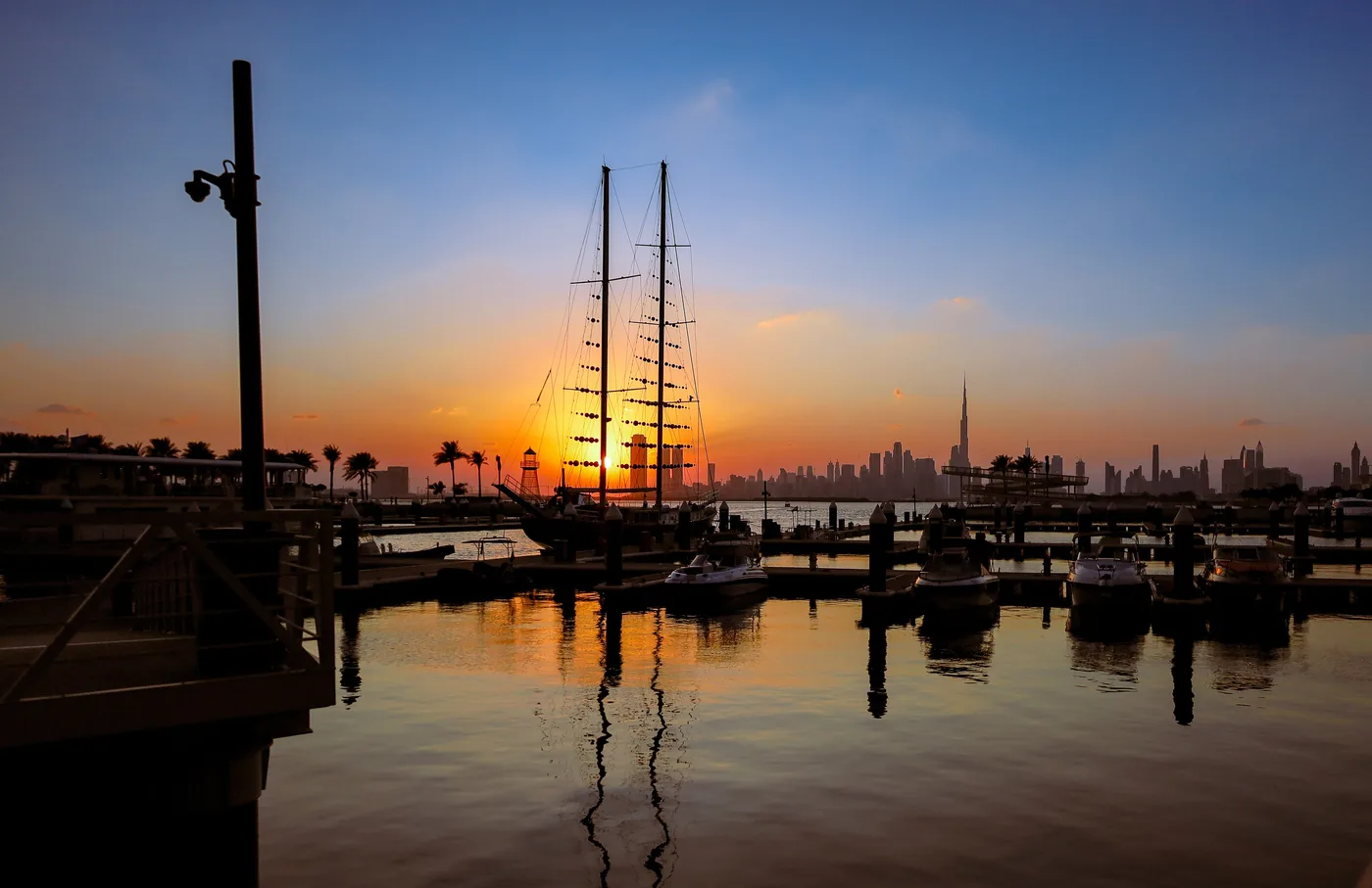 Sunset over Dubai Creek Harbour marina with a tall ship and the skyline beyond