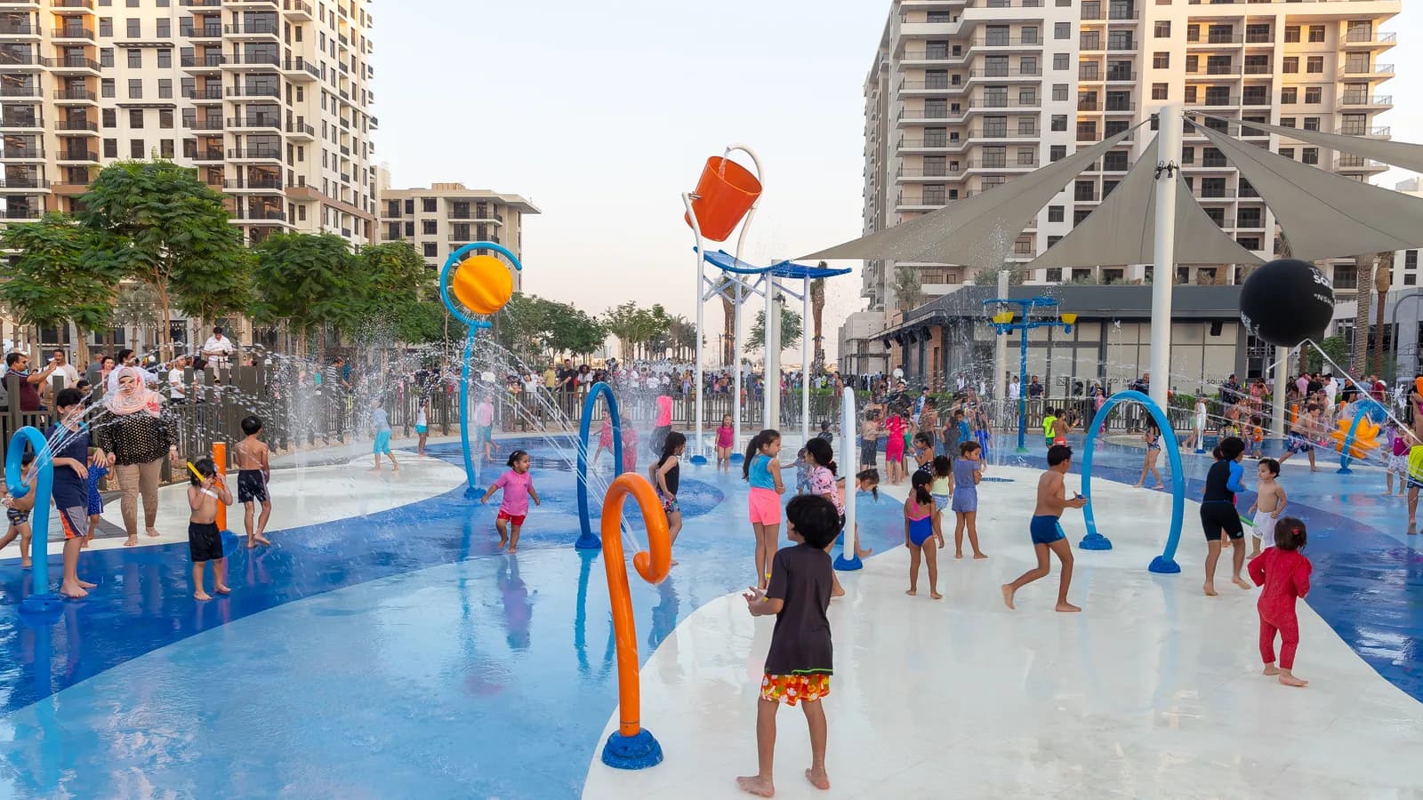Splash pad with shade sails and apartment blocks behind in Town Square Park
