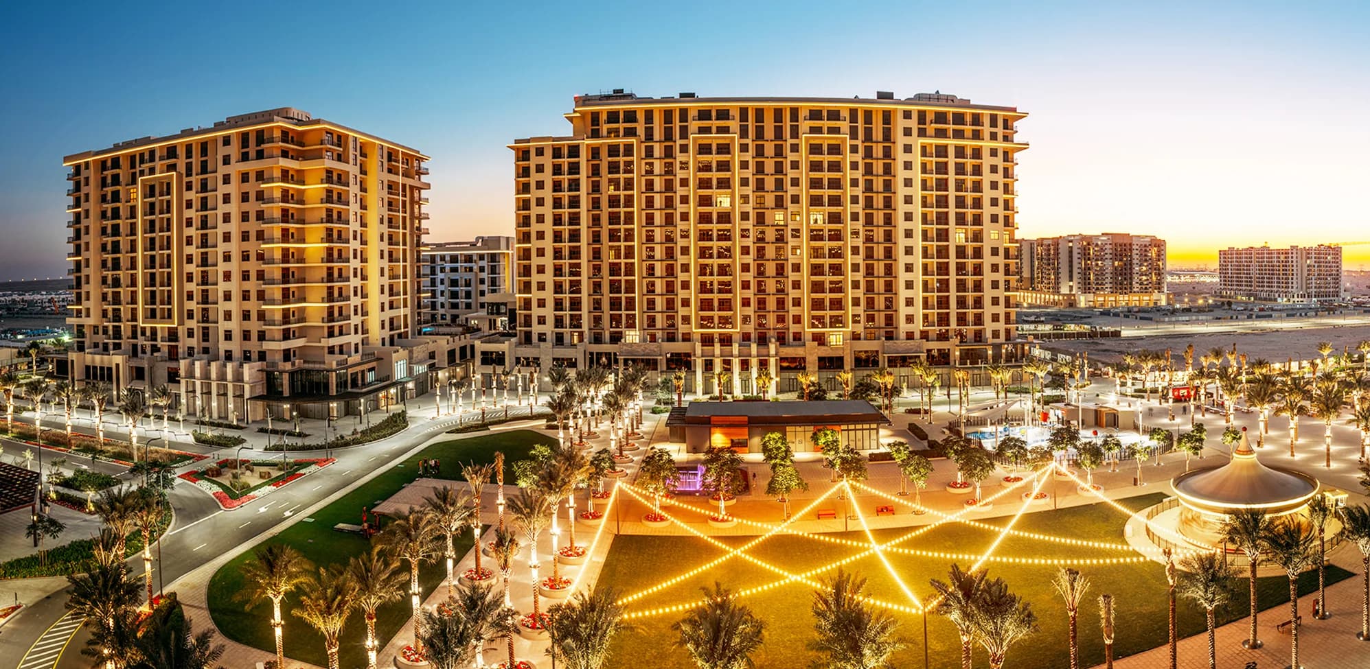 Town Square Dubai plaza and residential towers lit up at dusk